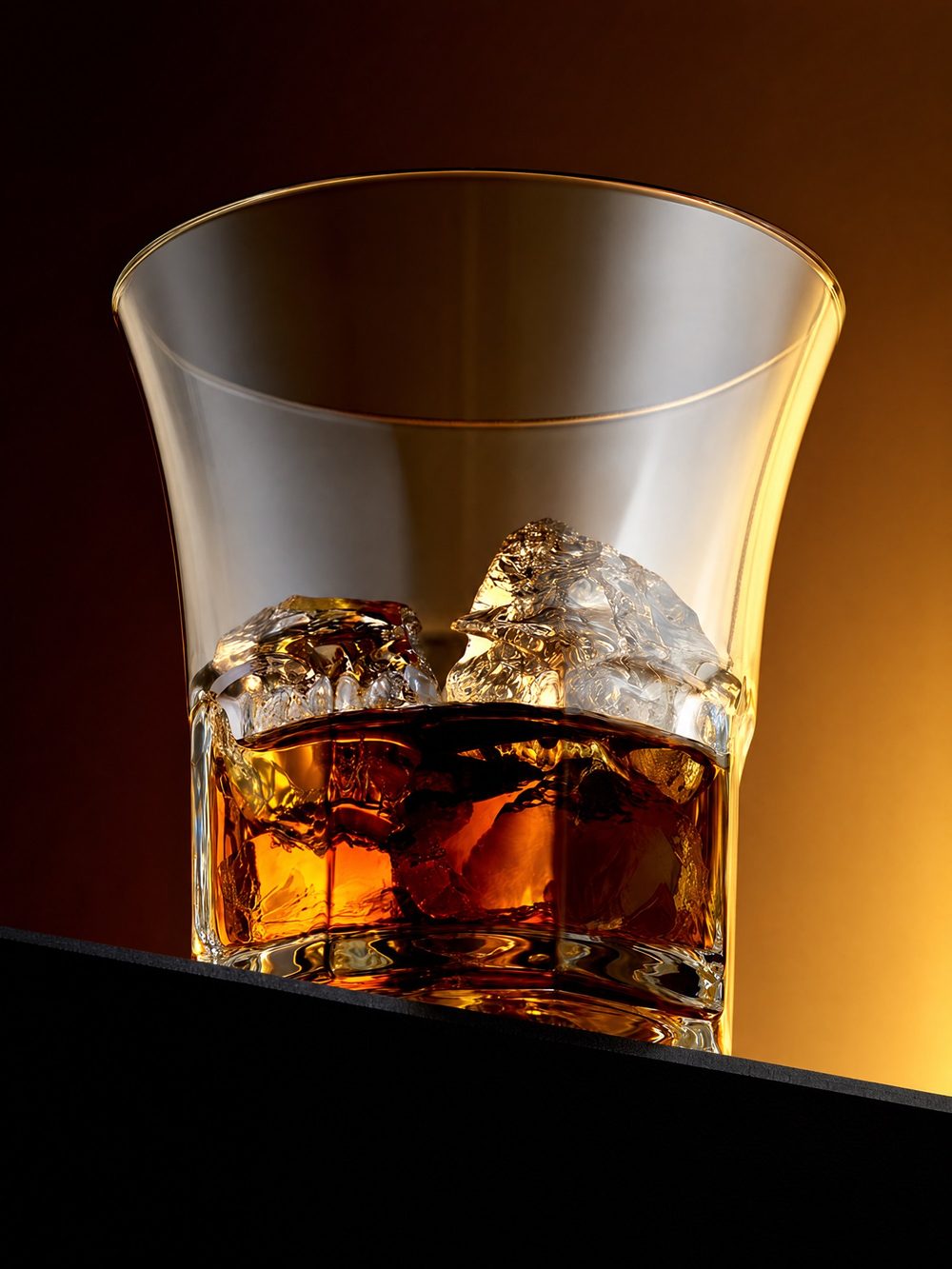 Whiskey on ice in a glass, lit against a warm amber backdrop
